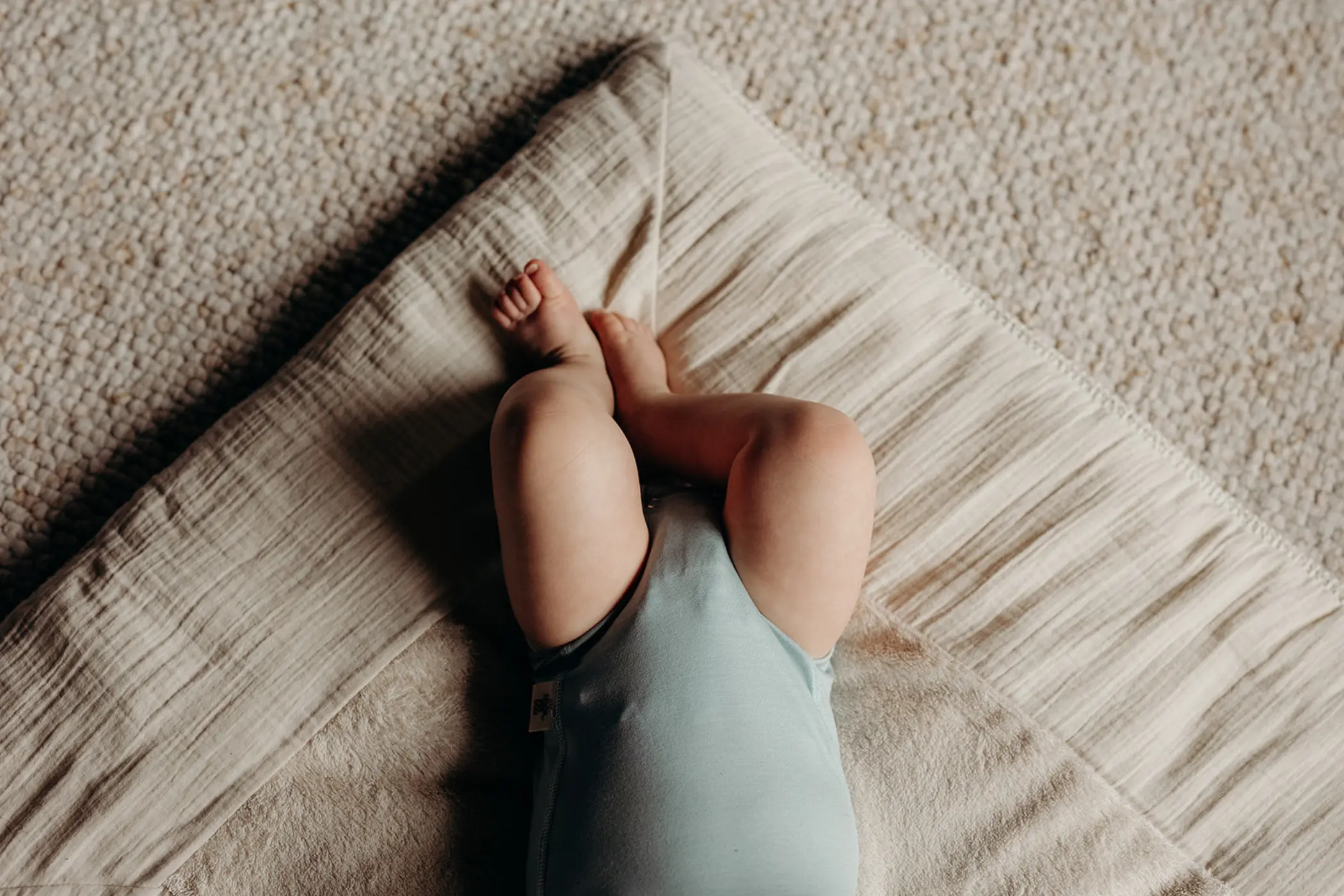 Baby in een mintgroene romper, van boven gezien op een mousseline doek