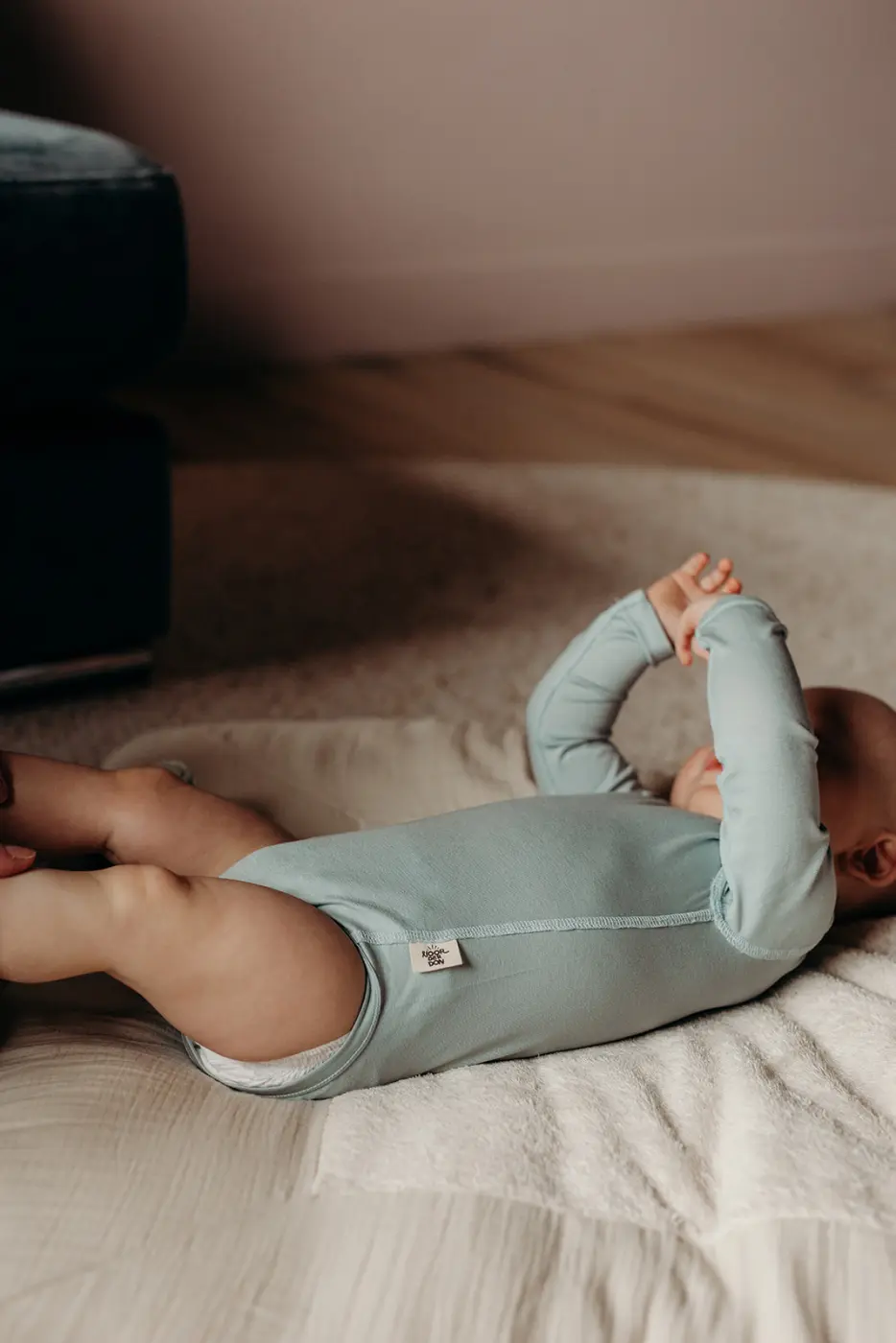 Baby in een mintgroene romper op een bed