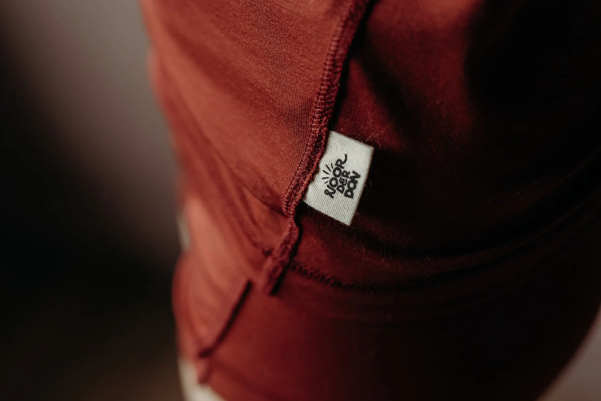 Detailfoto van het Noorderdon-label op een roestbruin shirt
