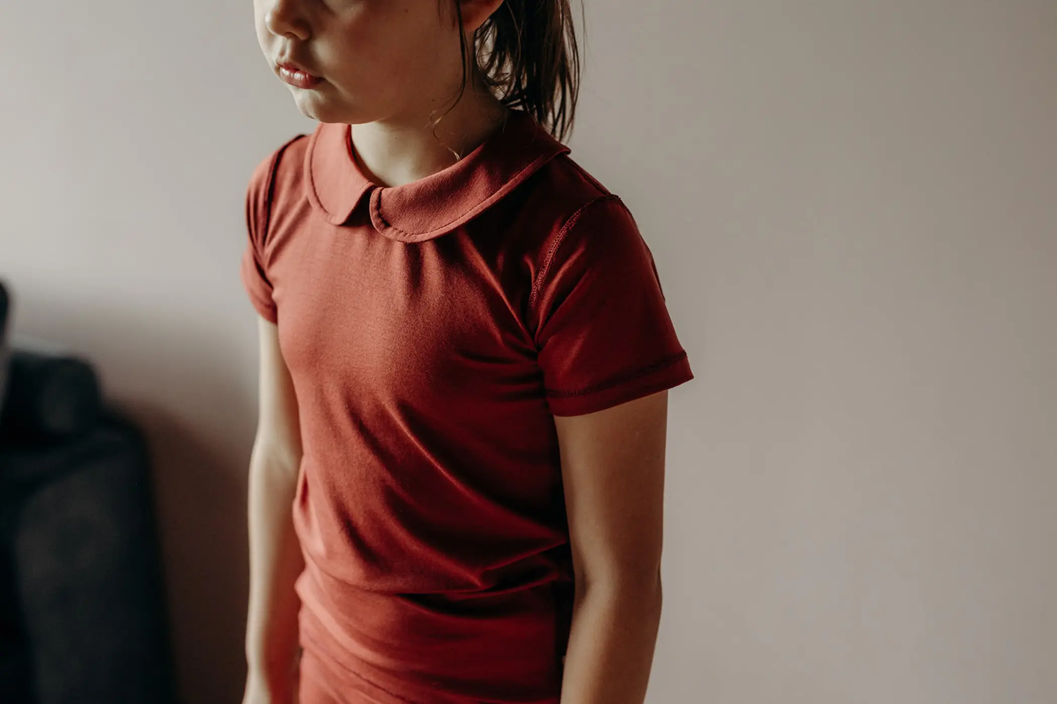 Kind in een roestbruin shirt met korte mouw en kraag, van opzij