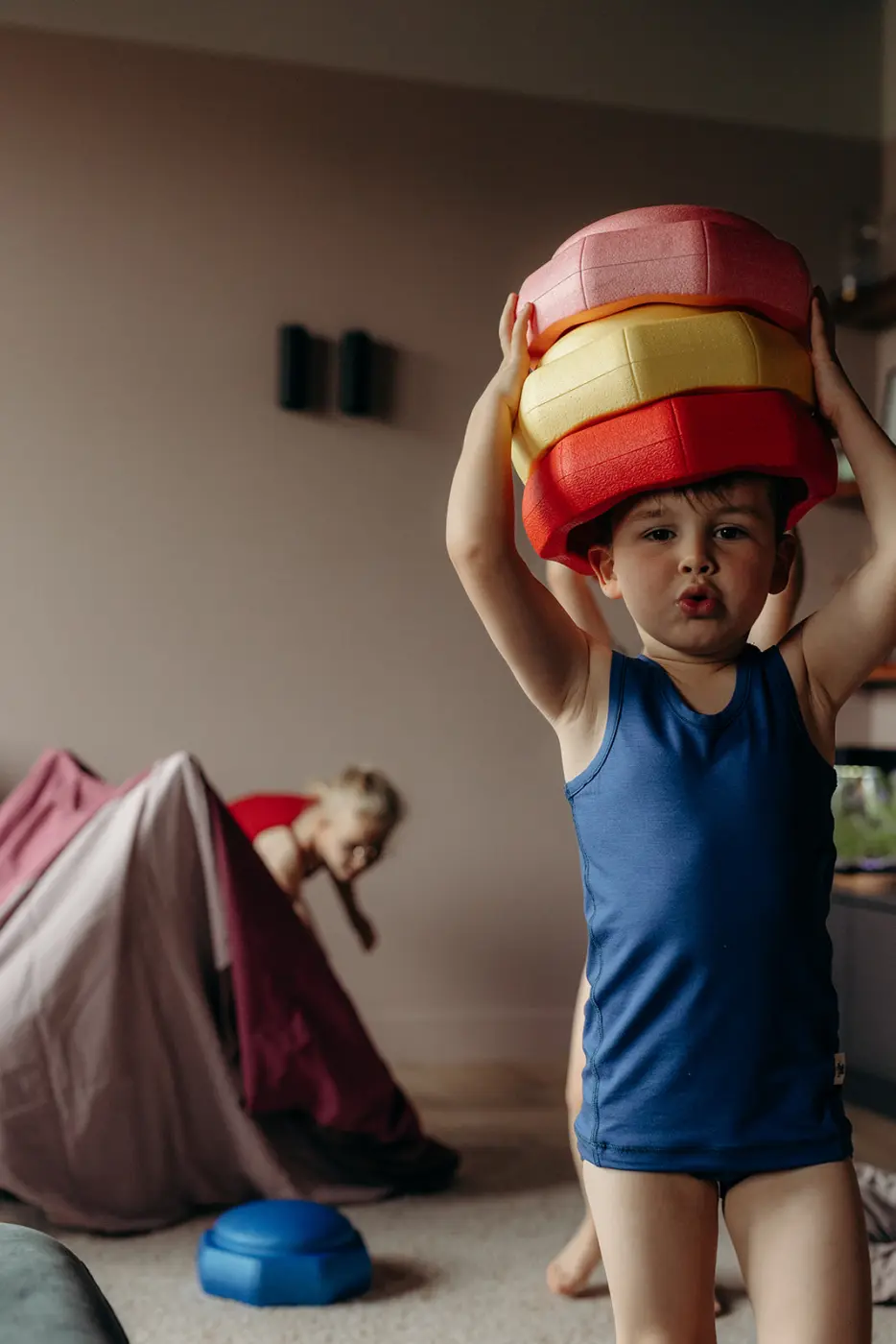 Kind in een donkerblauwe singlet houdt een stapel gekleurde speelschijven boven het hoofd